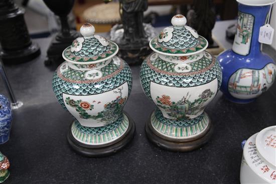 A pair of Chinese famille verte baluster vases and covers, late 19th century, 29.5cm, later drilled for lamp fittings, wood stands